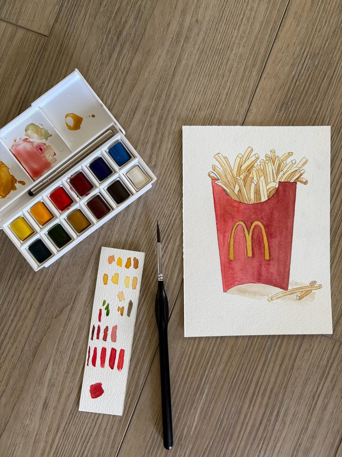 Paint palette beside a painting in progress
