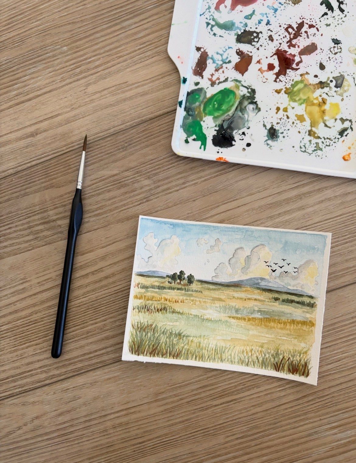 Watercolor of a golden field under clouds